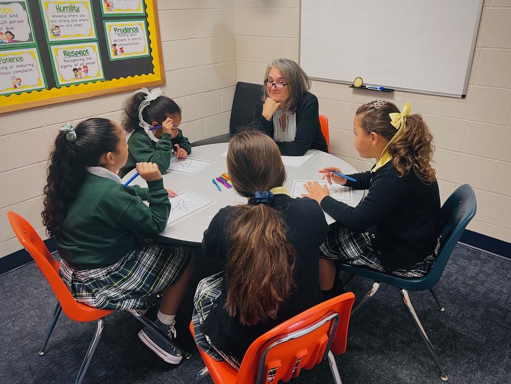 Students sitting around a table with a teacher.