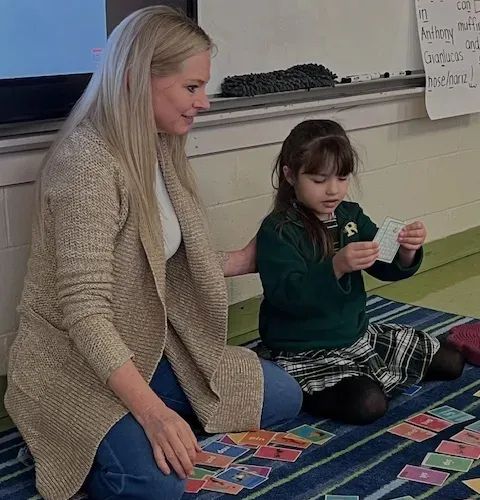 Students at a table reading with help from a teacher