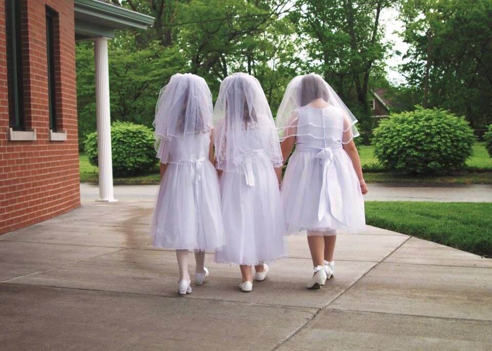 Three girls walking away in their white, first communion dresses